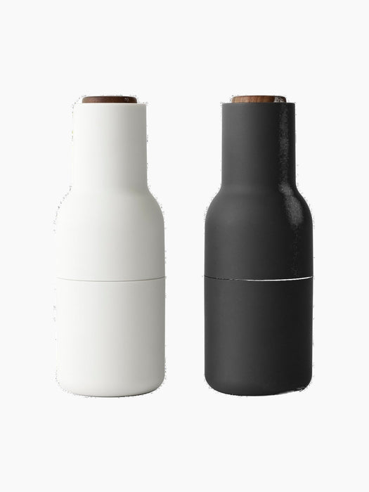 Front view of the Audo Bottle Grinder set in Ash and Carbon. The minimalist grinders feature a matte finish and walnut lids.