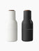 Front view of the Audo Bottle Grinder set in Ash and Carbon. The minimalist grinders feature a matte finish and walnut lids.