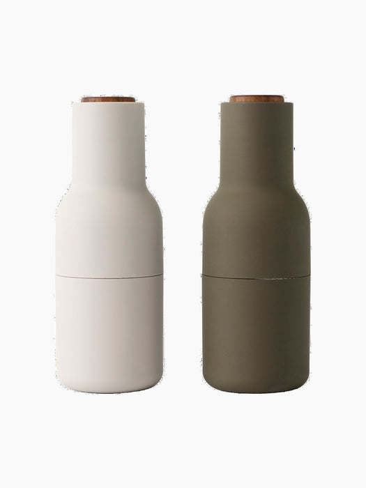 A pair of Audo CPH Bottle Grinders, one in beige and one in hunting green, both with solid walnut lids, shown from the front.