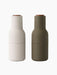 A pair of Audo CPH Bottle Grinders, one in beige and one in hunting green, both with solid walnut lids, shown from the front.