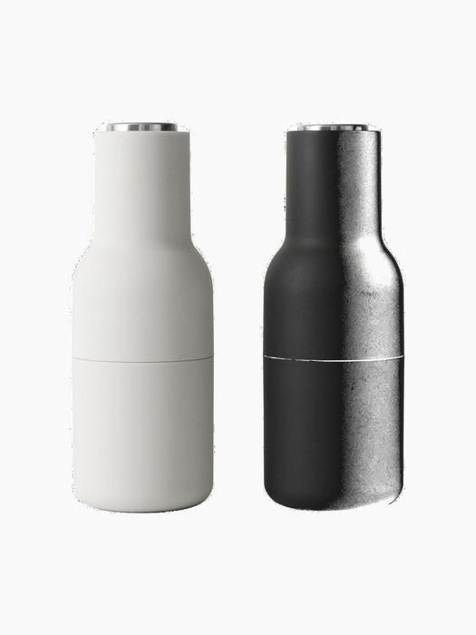 A pair of minimalist Bottle Grinders from Audo CPH, one in matte Ash and one in matte Carbon, both with brushed steel lids.
