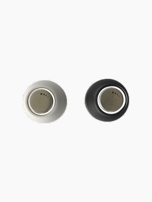 Top-down view of the Bottle Grinder in Ash and Carbon finishes, showcasing the brushed steel lids against a black background.