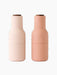 Front view of two Audo Bottle Grinders. One is a light nude pink and the other a darker blush nude, both with dark wood tops.