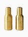 A pair of Bottle Grinders in brushed brass with walnut lids, presented side-by-side against a black background.