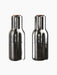 A front view of two Bottle Grinders made from bronzed brass with walnut lids, set against a black background.
