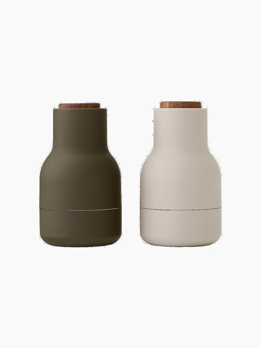 Bottle Grinders with walnut lids, one in matte hunting green and the other in matte beige, against a black background.