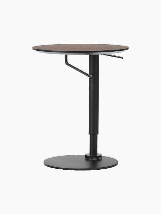 Angled view of the height-adjustable Branch Side Table with a dark round tabletop and black steel column with a flat base.