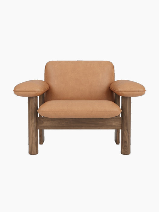 A front-on studio shot of the Brasilia Lounge Chair, Low Back. The chair has a solid walnut frame and camel upholstery.