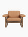 A front-on studio shot of the Brasilia Lounge Chair, Low Back. The chair has a solid walnut frame and camel upholstery.