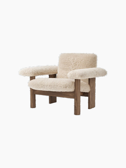 An angled view of the Brasilia Lounge Chair, Low Back, upholstered in light sheepskin with a dark solid wood frame.