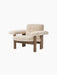 An angled view of the Brasilia Lounge Chair, Low Back, upholstered in light sheepskin with a dark solid wood frame.