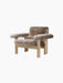 The Brasilia Lounge Chair, Low Back, in brown sheepskin with a natural oak frame, shown at an angle on a black background.