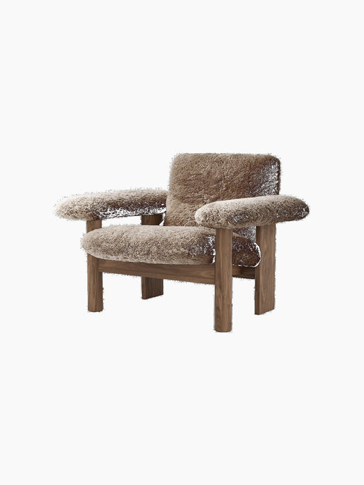 The Brasilia Lounge Chair, Low Back, with a dark wood frame and brown sheepskin upholstery, viewed from an angle.
