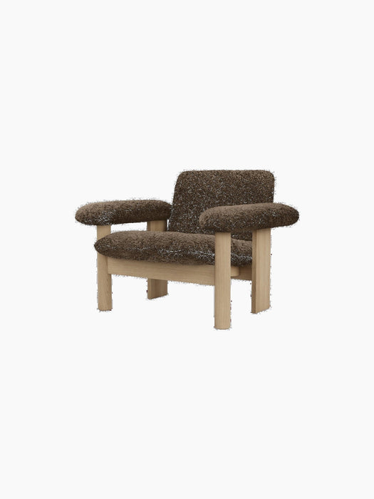 An angled view of the Brasilia Lounge Chair with a low back, featuring a natural oak frame and brown sheepskin upholstery.
