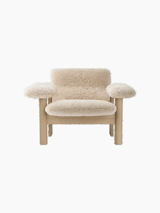 Front-on shot of the Brasilia Lounge Chair, Low Back. It has a light oak frame and is upholstered in fluffy, beige sheepskin.