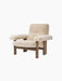 Angled view of the Brasilia Lounge Chair, featuring a high back and cushioned seat in natural sheepskin and a walnut frame.