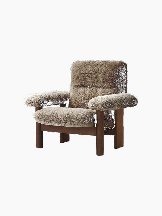 The Brasilia Lounge Chair in brown sheepskin. It has a high back, exaggerated armrests, and a sturdy dark wooden frame.