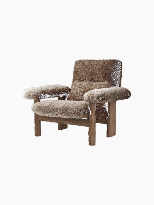 A Brasilia Lounge Chair, High Back, brown sheepskin upholstery, walnut frame, shown from an angle on a black background.