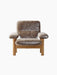 Front view of the Brasilia Lounge Chair with a natural oak frame and thick brown sheepskin upholstery on a black background.