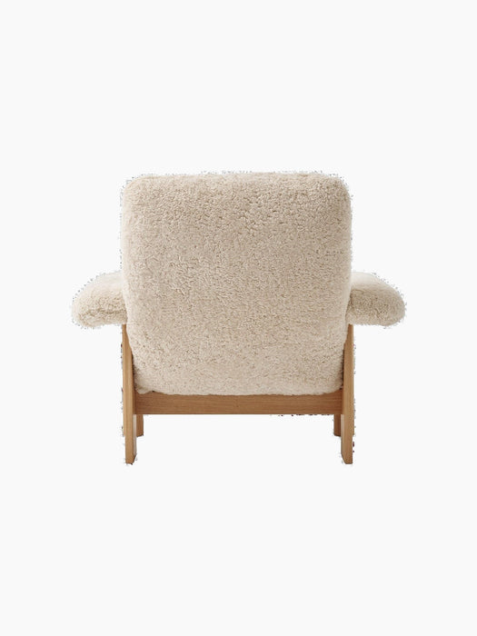 Rear view of the Brasilia Lounge Chair, upholstered in fluffy Sheepskin Nature fabric with a sturdy Natural Oak wooden frame.