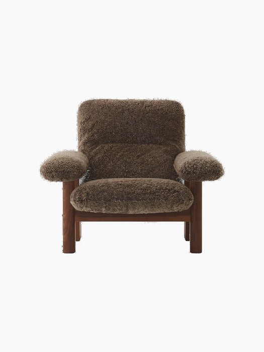 The Brasilia Lounge Chair shown from the front, featuring a dark stained oak frame and plush Root sheepskin upholstery.