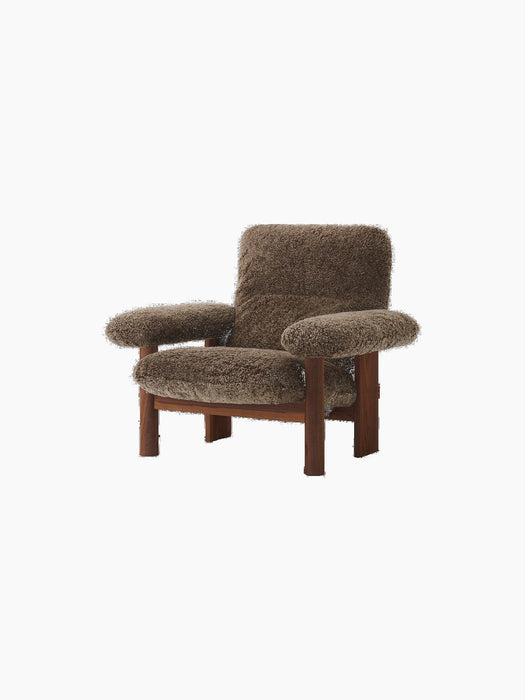 An angled view of the Brasilia Lounge Chair with a high back, featuring a dark walnut frame and plush, brown Root sheepskin.