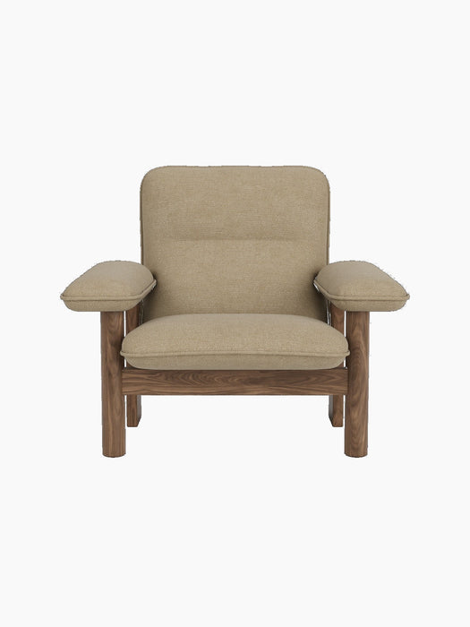 Front view of the Brasilia Lounge Chair with a walnut frame and beige Audo Bouclé 02 upholstery on a black background.