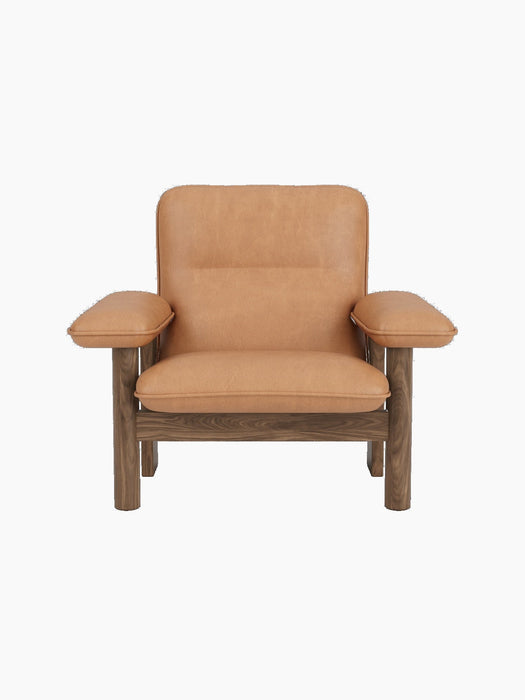 Front view of the Brasilia Lounge Chair in walnut with plush, camel leather upholstery, shown against a black background.