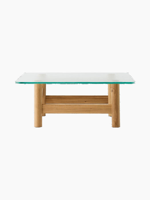 Side view of the Brasilia Lounge Table. It has a thick glass top and a solid natural oak base with four stout, rounded legs.
