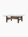 Side view of the Brasilia Lounge Table, featuring a square glass top with rounded corners resting on a dark wood base.