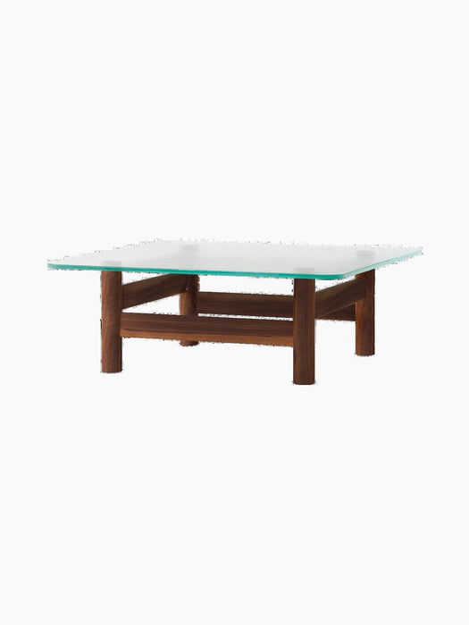 Front-angle view of the Brasilia Lounge Table in walnut, with a square glass top and solid wood frame, on a black background.