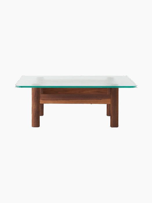 Front view of the Brasilia Lounge Table, showing its solid walnut base and square, tempered glass top on a black background.