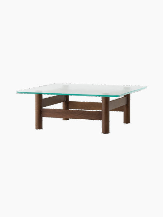 A front-angle view of the Brasilia Lounge Table, featuring a dark wood base with four stout legs and a square glass top.