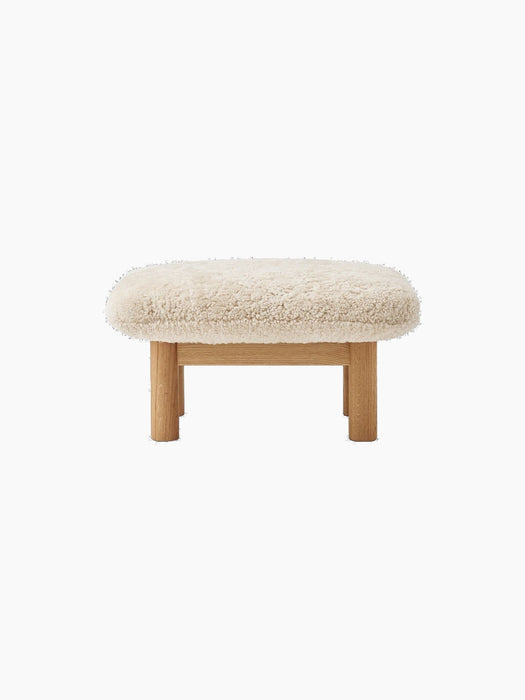 Front view of the Brasilia Lounge Ottoman, featuring a fluffy, off-white Sheepskin Nature cushion on a natural oak frame.