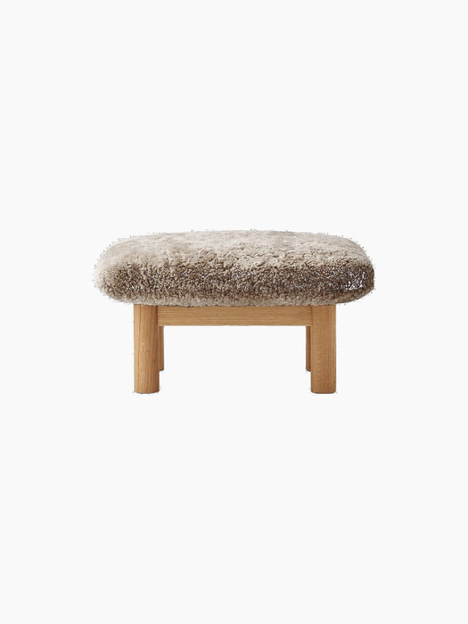 Front view of the Brasilia Ottoman, featuring a plush sheepskin cushion in a natural colour on a natural oak wood frame.