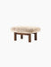 Brasilia Ottoman with a plush Sheepskin Root cushion and four robust, cylindrical legs in dark stained oak, at an angle.