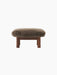 A front-on view of the Brasilia Ottoman, upholstered in brown sheepskin, with a dark walnut frame and four thick legs.