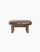 Brasilia Ottoman in Sheepskin, seen from the back. A thick, brown sheepskin seat on a wooden frame with four legs.