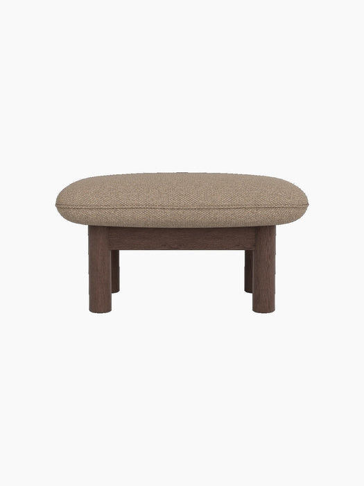 Side view of the Brasilia Ottoman in dark stained oak with a textured Logan Flint textile cushion, on a black background.