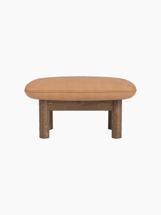 Brasilia Ottoman with a solid walnut frame, four thick cylindrical legs, and a soft, rounded camel leather cushion.