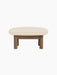 Front view of the Brasilia Ottoman, featuring a thick, light-coloured Logan Jasmine textile cushion on a walnut wood frame.