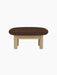 Side profile of the Brasilia Ottoman, upholstered in brown bouclé fabric with a natural oak frame and four cylindrical legs.