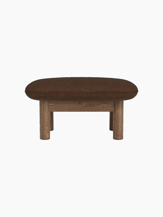 A side view of the Brasilia Ottoman with a walnut frame, four thick cylindrical legs and a plush cushion in brown bouclé.