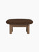 A side view of the Brasilia Ottoman with a walnut frame, four thick cylindrical legs and a plush cushion in brown bouclé.