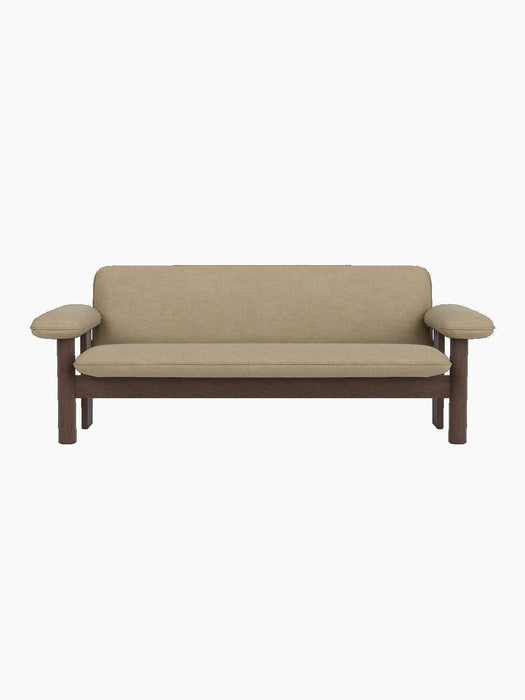 A front view of the Brasilia Sofa, featuring a dark stained oak frame with thick cushions upholstered in Audo Bouclé 02.