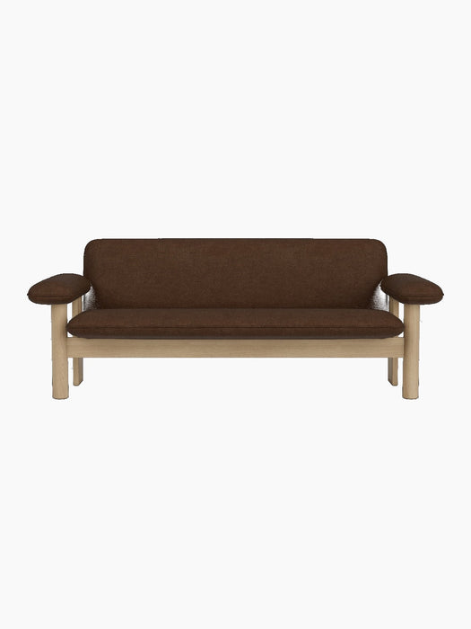 A front-on view of the Brasilia Sofa with a natural oak frame, exaggerated armrests and brown Audo Bouclé 07 upholstery.