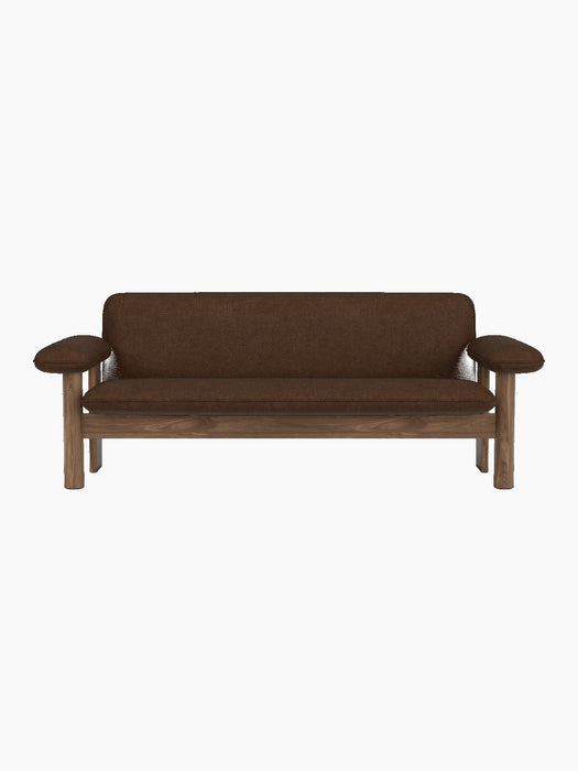 A front view of the Brasilia Sofa with a solid walnut frame and brown Audo Bouclé 07 upholstery against a black background.