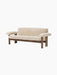 The Brasilia Sofa in Sheepskin at an angle, with a dark wood frame and plush, light sheepskin upholstery.