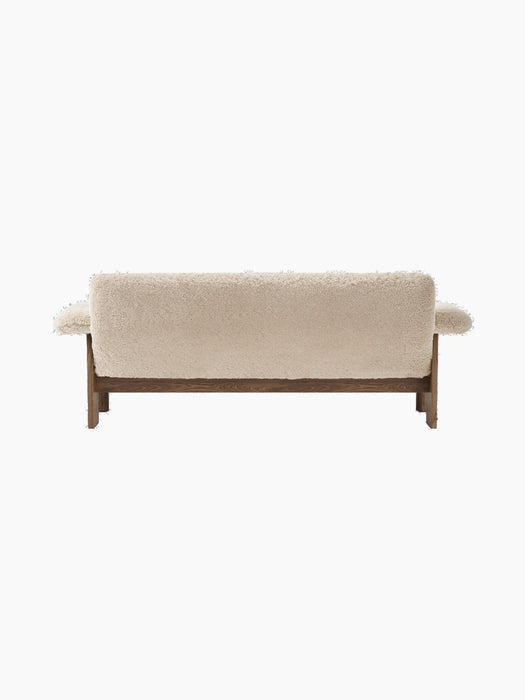 Back view of the Brasilia Sofa, upholstered in light sheepskin, showing the dark solid wood frame and rounded armrests.