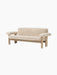 Angled view of the Brasilia Sofa, upholstered in plush cream Sheepskin with a light oak frame and large rounded armrests.